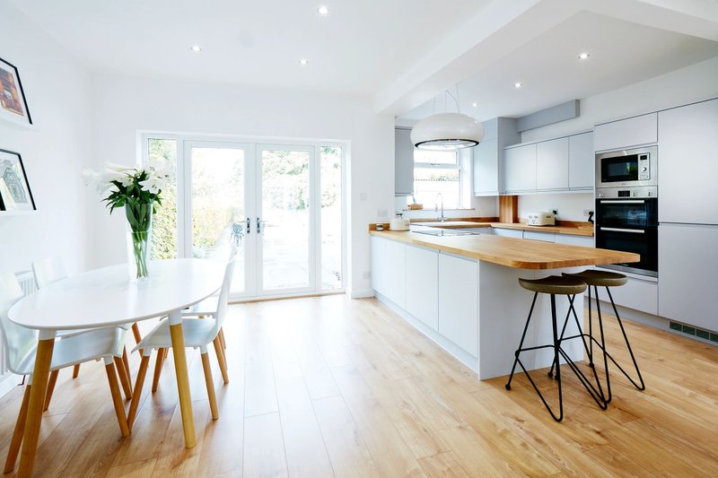 Bright modern kitchen with white cabinetry and glass doors